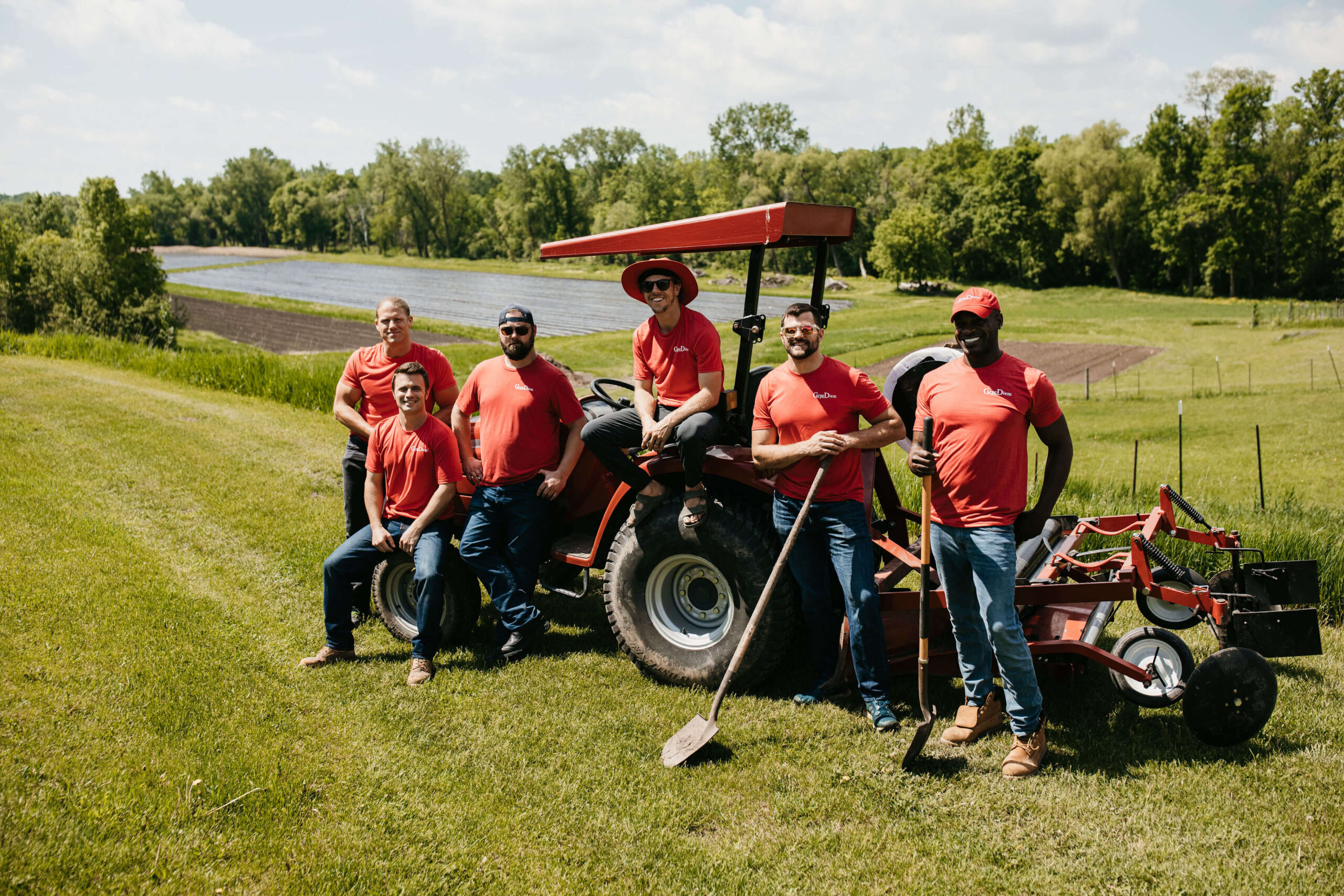 Carpe Diem team sitting on a tracker in a grass field