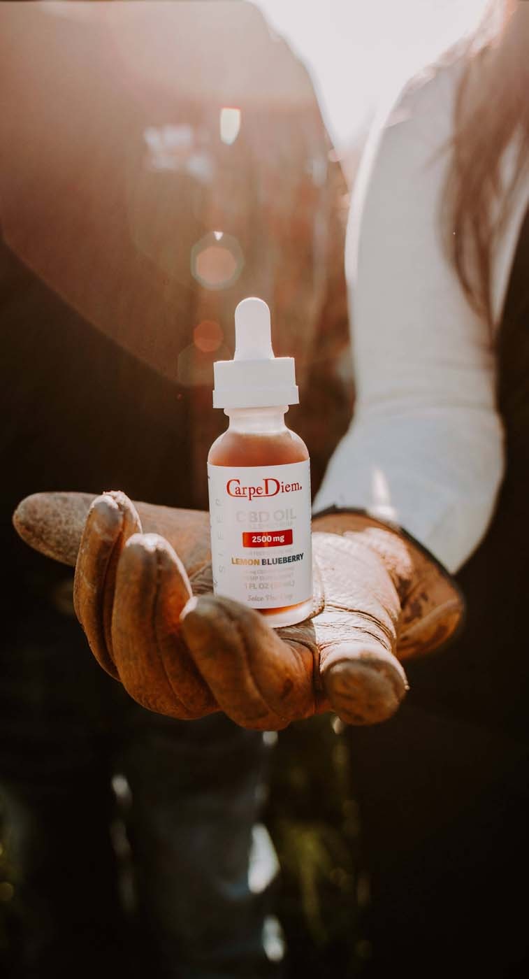 Person holding leather glove holding Carpe Diem CBD Oil