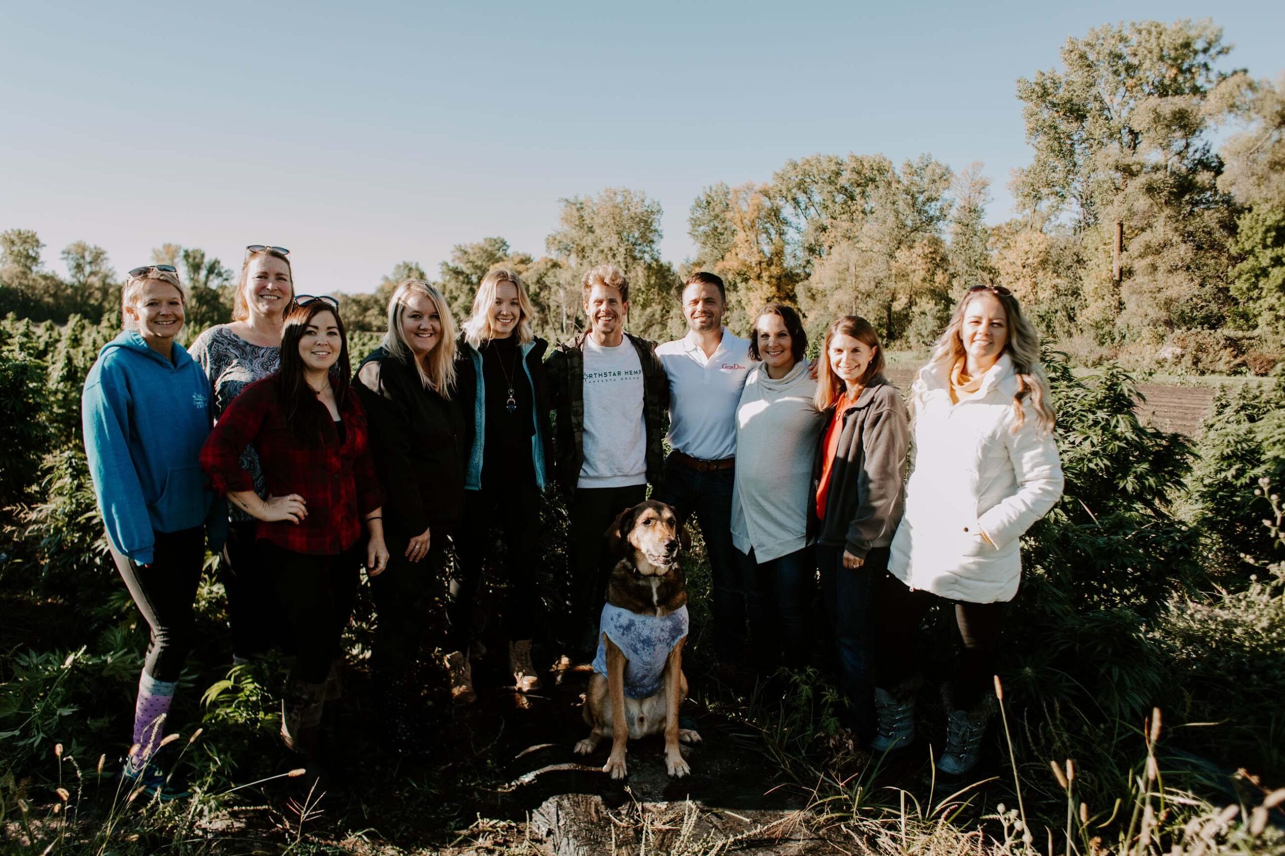 Carpe Diem team and dog posing in front of a field