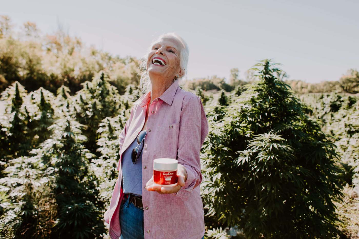 Older woman holding CBD lotion and laughing