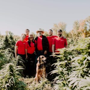 Carpe Diem team and dog standing in a hemp field
